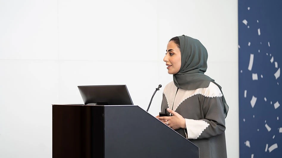 a woman wearing a head covering behind a podium