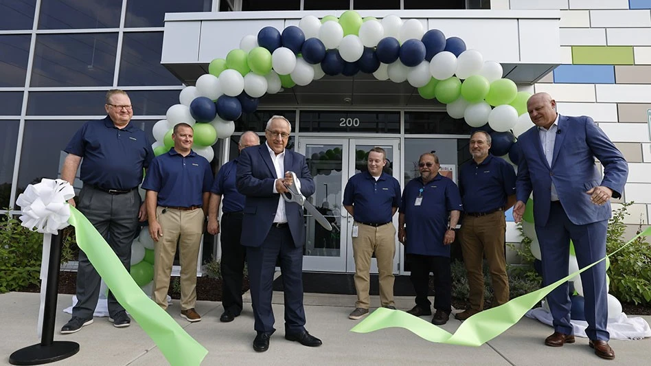 people stand before a ballon arch and a ribbon that has been cut with large scissors