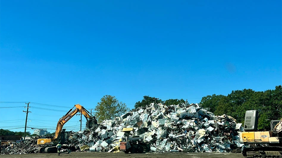 Two material handlers surround a pile of scrap metal under a clear blue sky at Empire Service Inc.'s Norfolk, Virginia, scrap yard.