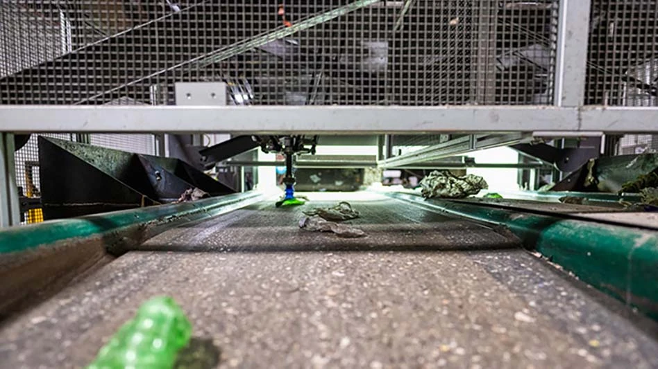 conveyor belt with plastic on it and a robot above it