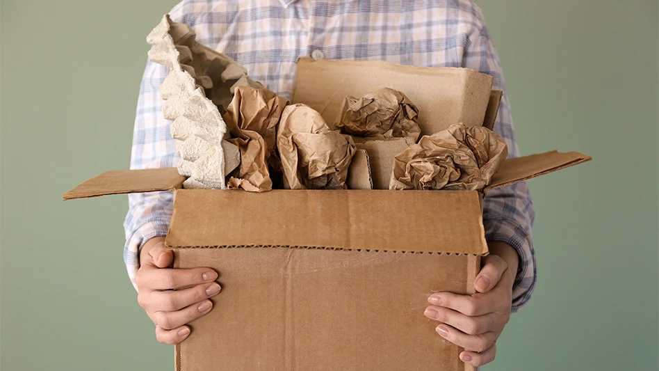 A man holds a cardboard box full of paper scrap