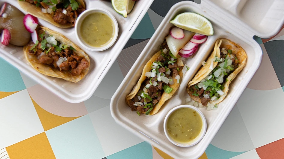 Better Earth's new two- and three-taco clamshell containers, with tacos inside of them, sitting on a table.