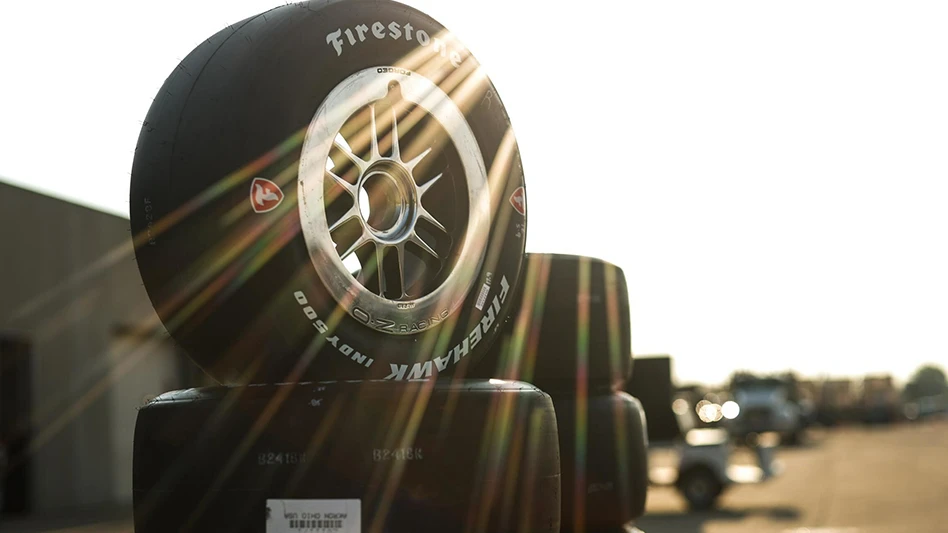 A stack of Firestone Firehawk tires with a sunset in the background.