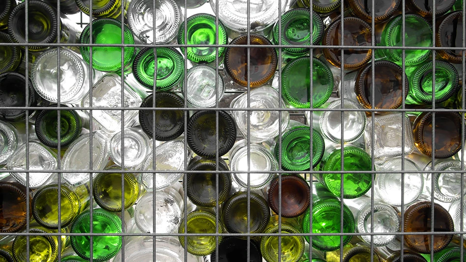 Glass bottles on top of a wire rack viewed from below.