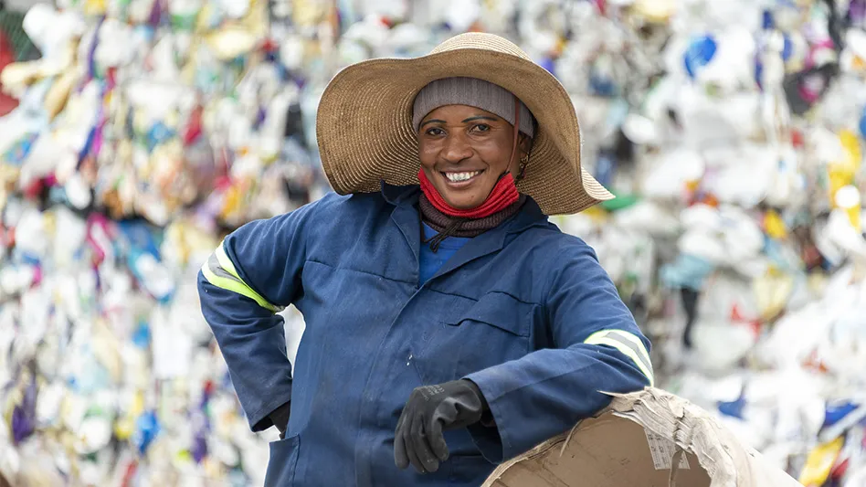An Mpact Recycling worker poses in front of a heap of collected recyclables