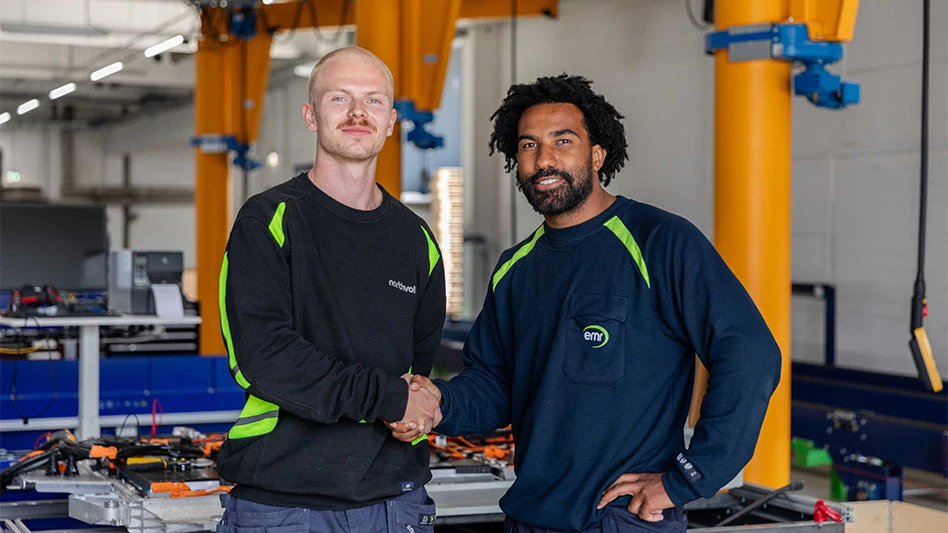 Employees from EMR and Northvolt shake hands at an EV battery recycling facility.