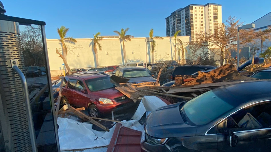 hurricane damage with destroyed cars in foreground and building in background