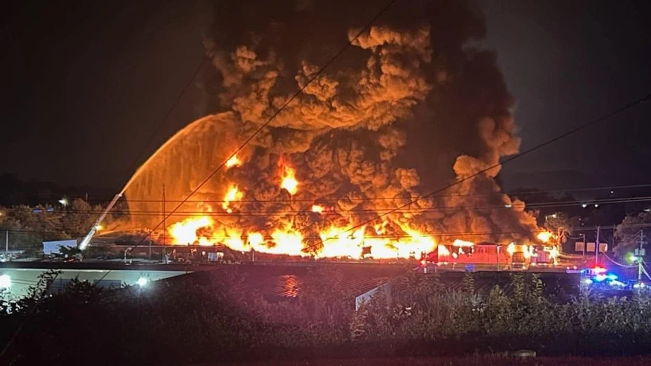 recycling facility fire at night with fire crews fighting it with hoses