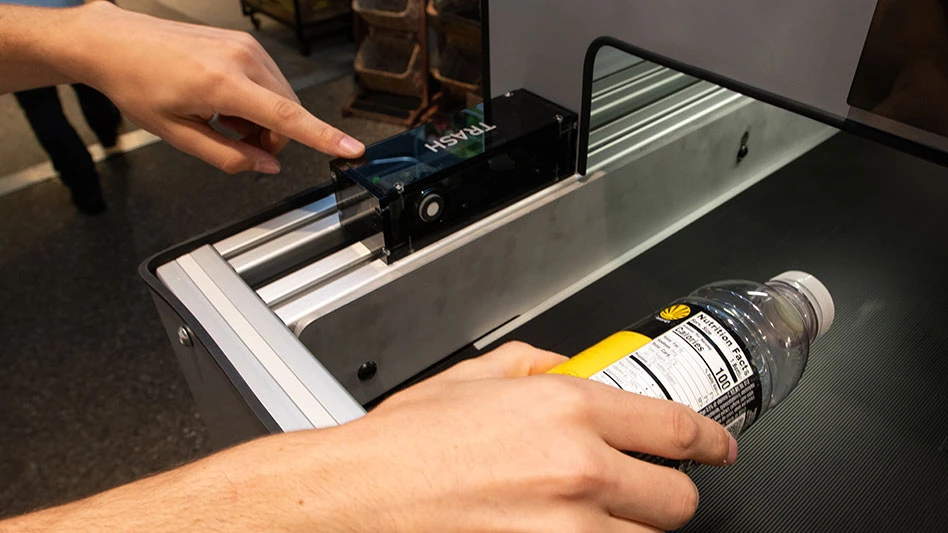 a hand holds a glass bottle in a machine