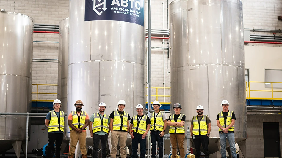 a group of people in yellow vests and hard hats stand in facility