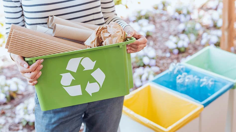 person holding green recycling bin with packaging overflowing