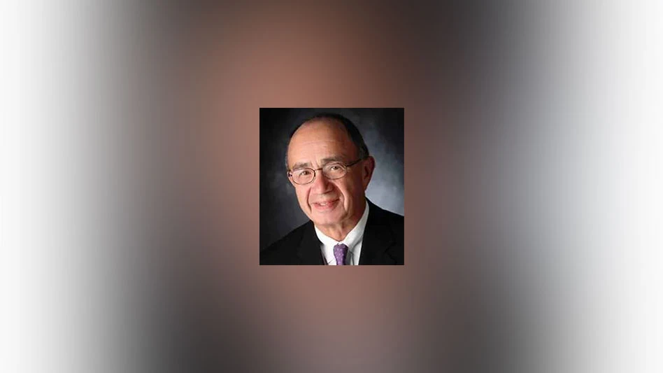 a smiling, bald white man with glasses wearing a white shirt, dark tie and black jacket