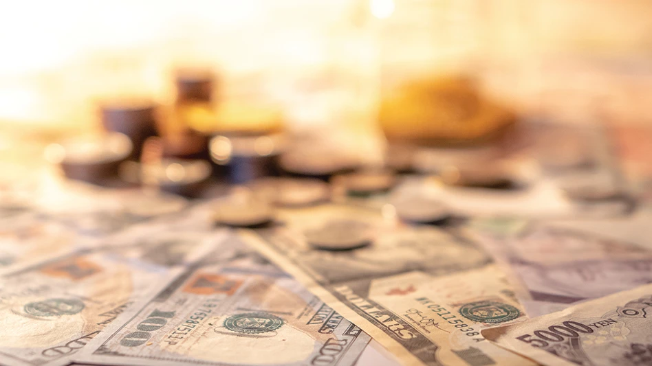 Various types of international money under a light, fading out near the back.