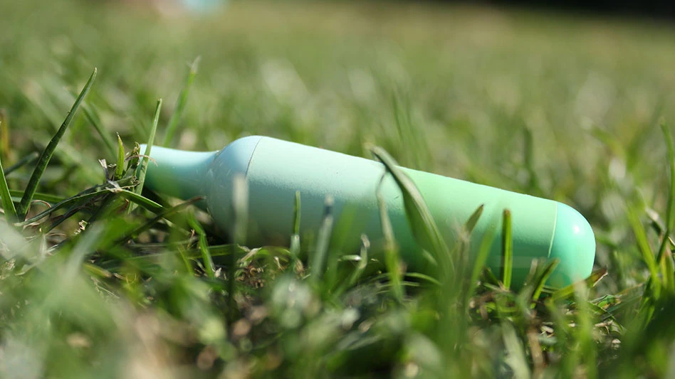 a green disposable vape discarded in the grass