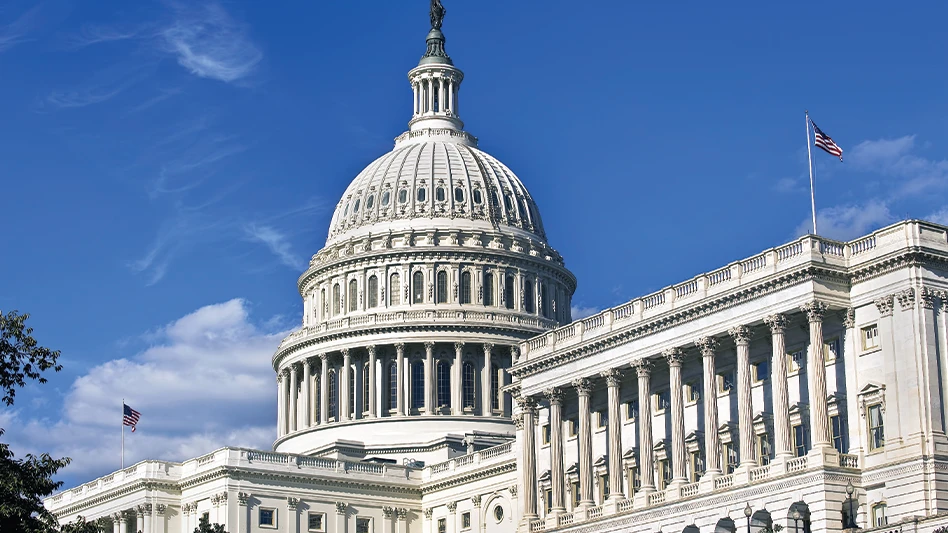 The U.S. Capitol building, from a side angle, under a clear, blue sky.