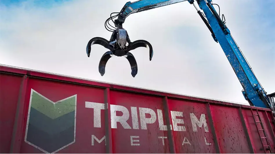 a rail car with the Triple M Metal logo on it with a scrap handler eqipped with a grapple