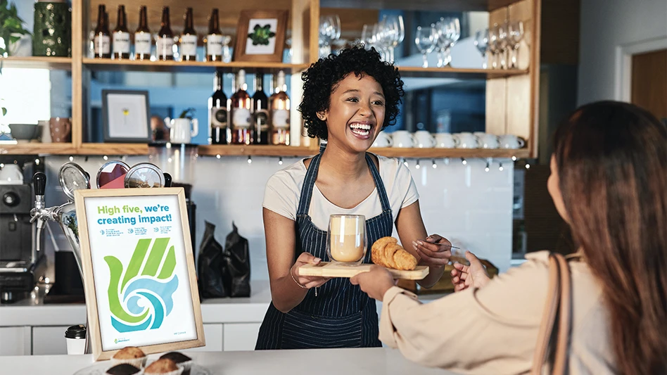 A worker behind a counter at a restaurant hands a dish to a customer.