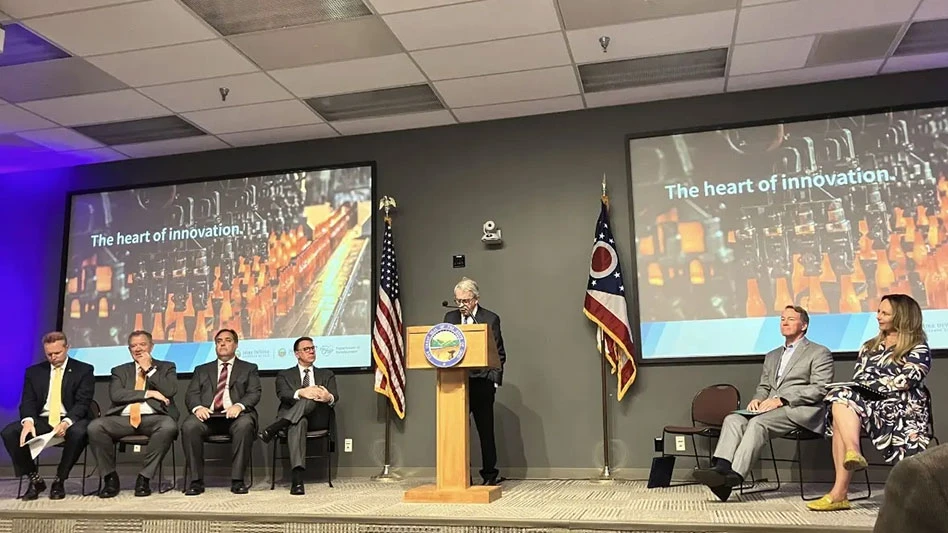 mike dewine speaks at a lecturn with people seated to his left and right