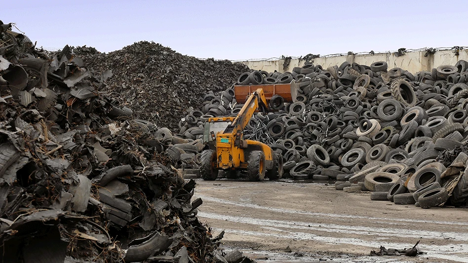 piles of tires for recycling with a loader working among them