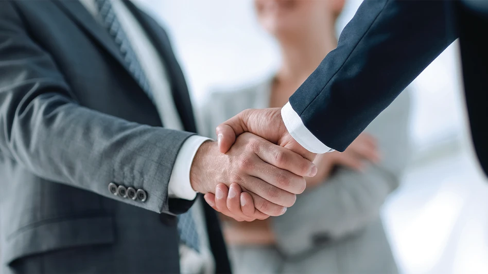 Two businessmen shake hands in an office.