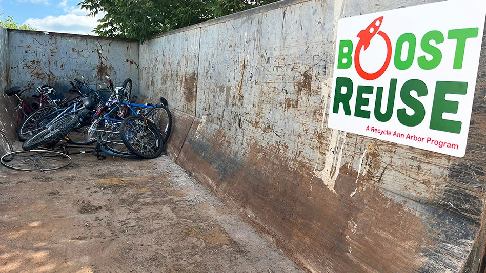 a roll-off container with bicycles inside and the boost reuse logo to the right of the container