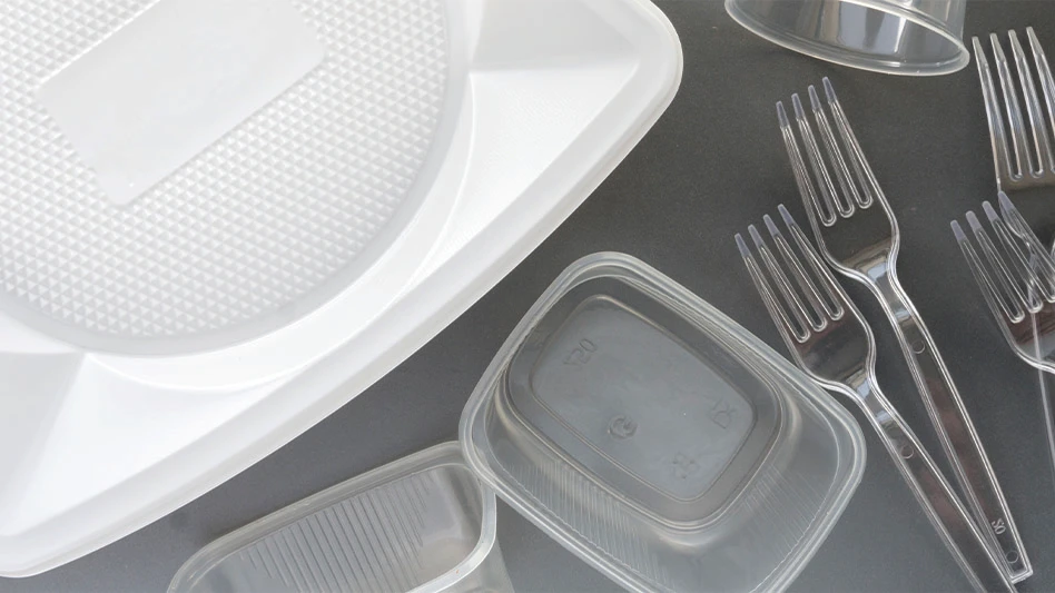 Plastic cutlery and plastic containers on a gray surface.