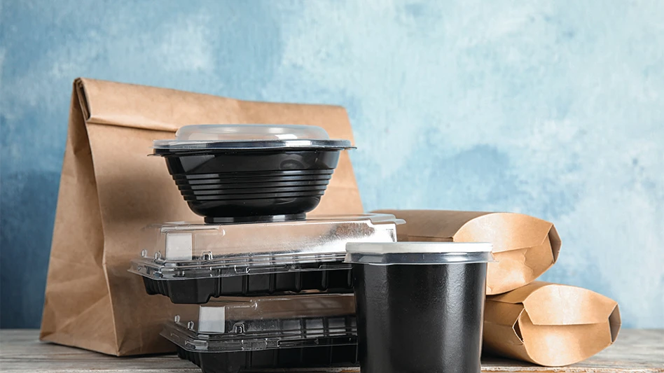 Various paper and plastic food containers stacked on a table.