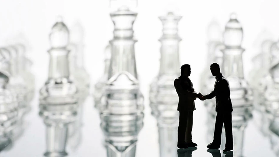 two black figurines shake hands in front of crystal pieces on a chessboard