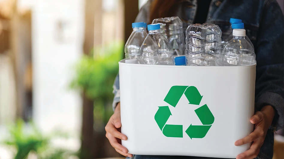 A woman collecting and holding recyclable garbage plastic bottles in a trash bin at home.