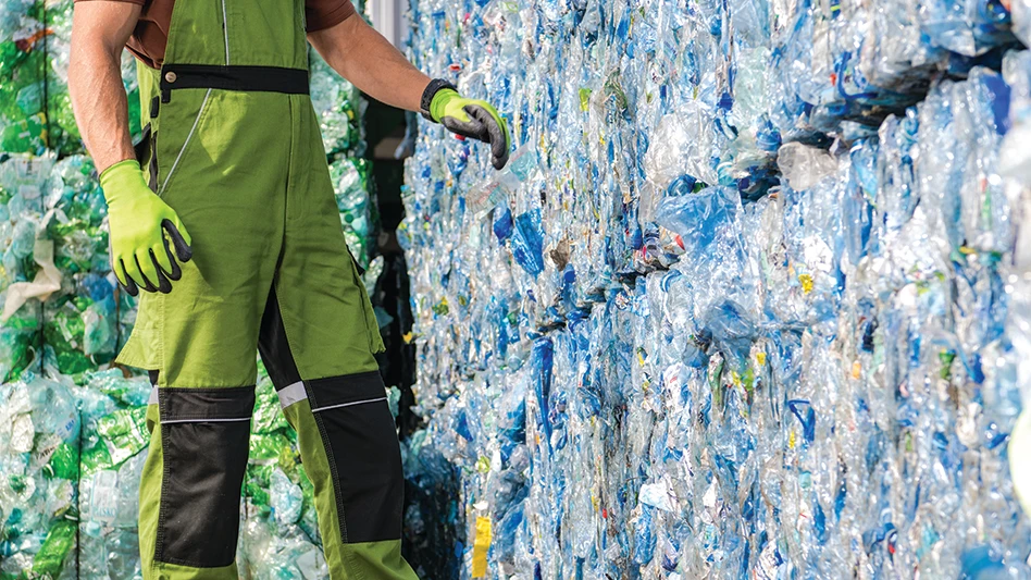 A recycling facility employee walks past bales of PET.