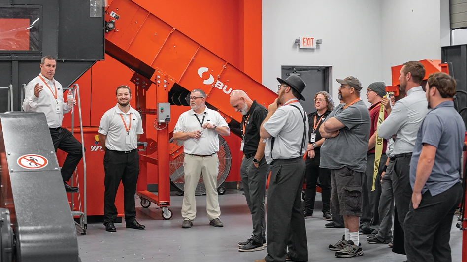 People gather around a large material shredder.