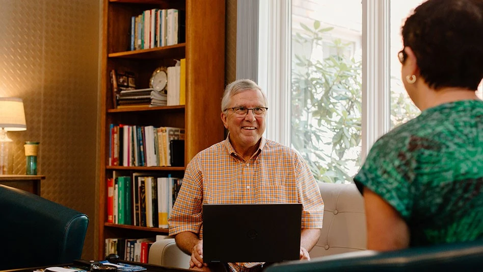 man on a computer faces woman with back to camera