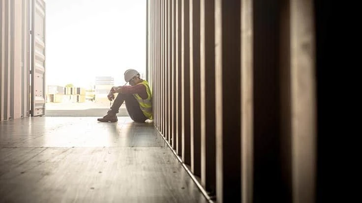 Construction worker by shipping container